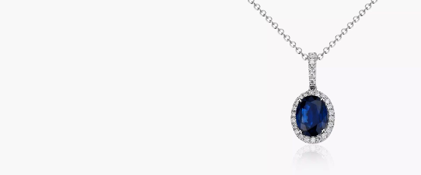 A blue oval sapphire gemstone and diamond pendant